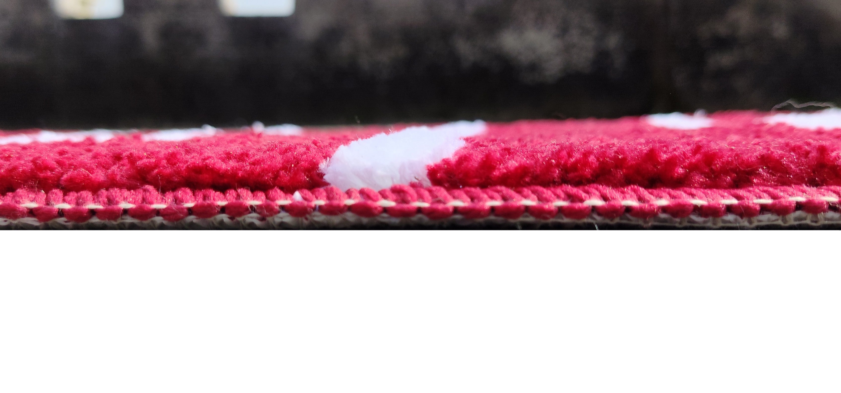 Close-up view of a modern rug with red and white stripes, showcasing the texture of the microfiber material.